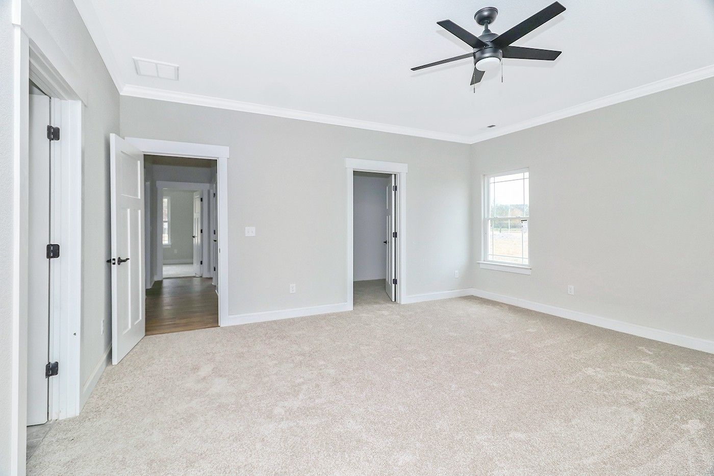 An empty bedroom with a ceiling fan and a window.