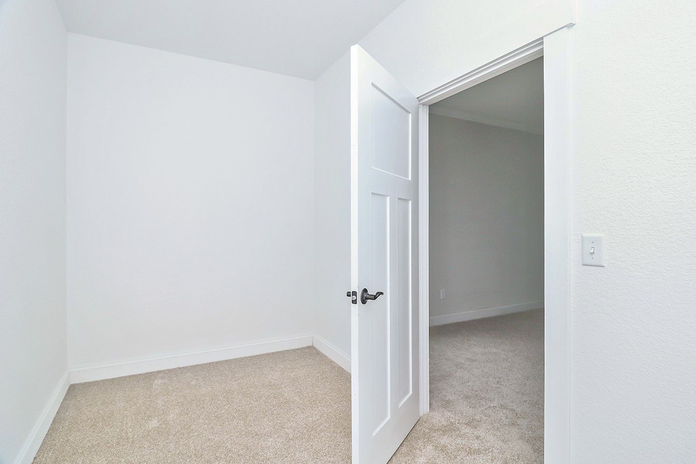 An empty room with a door open and a carpeted floor.