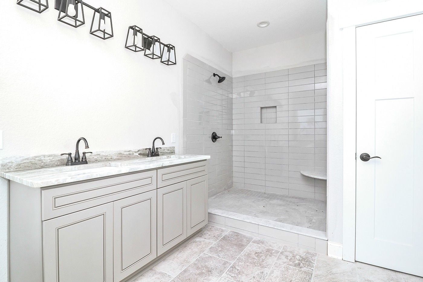 A bathroom with two sinks and a walk in shower.