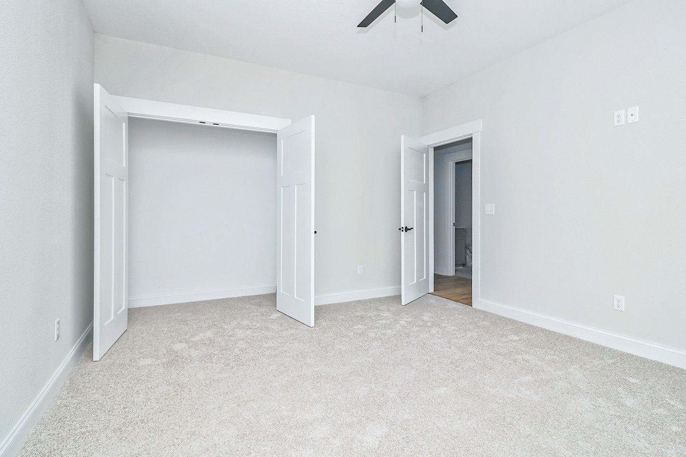 An empty bedroom with a ceiling fan and a closet.