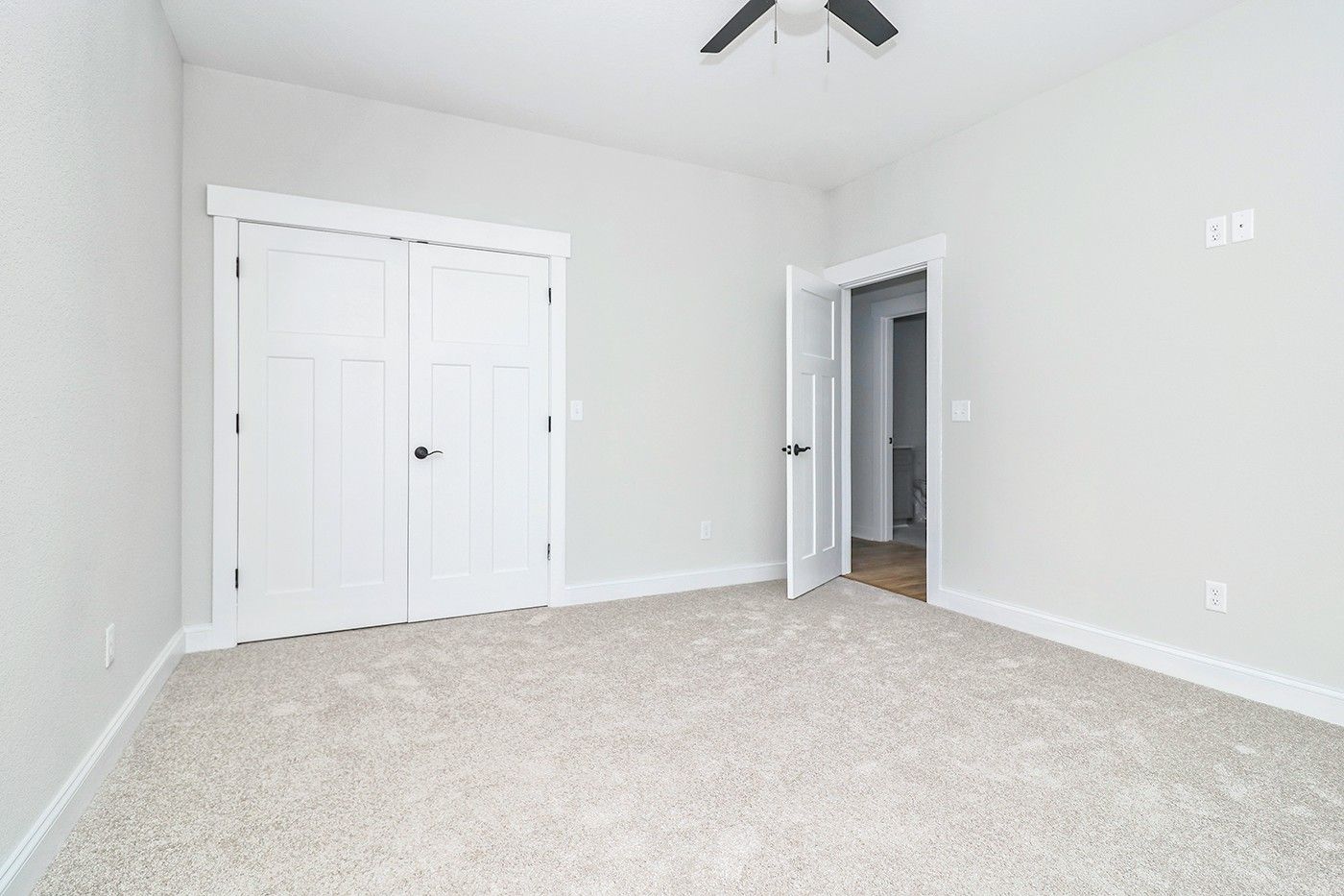 An empty bedroom with a ceiling fan and a large closet.
