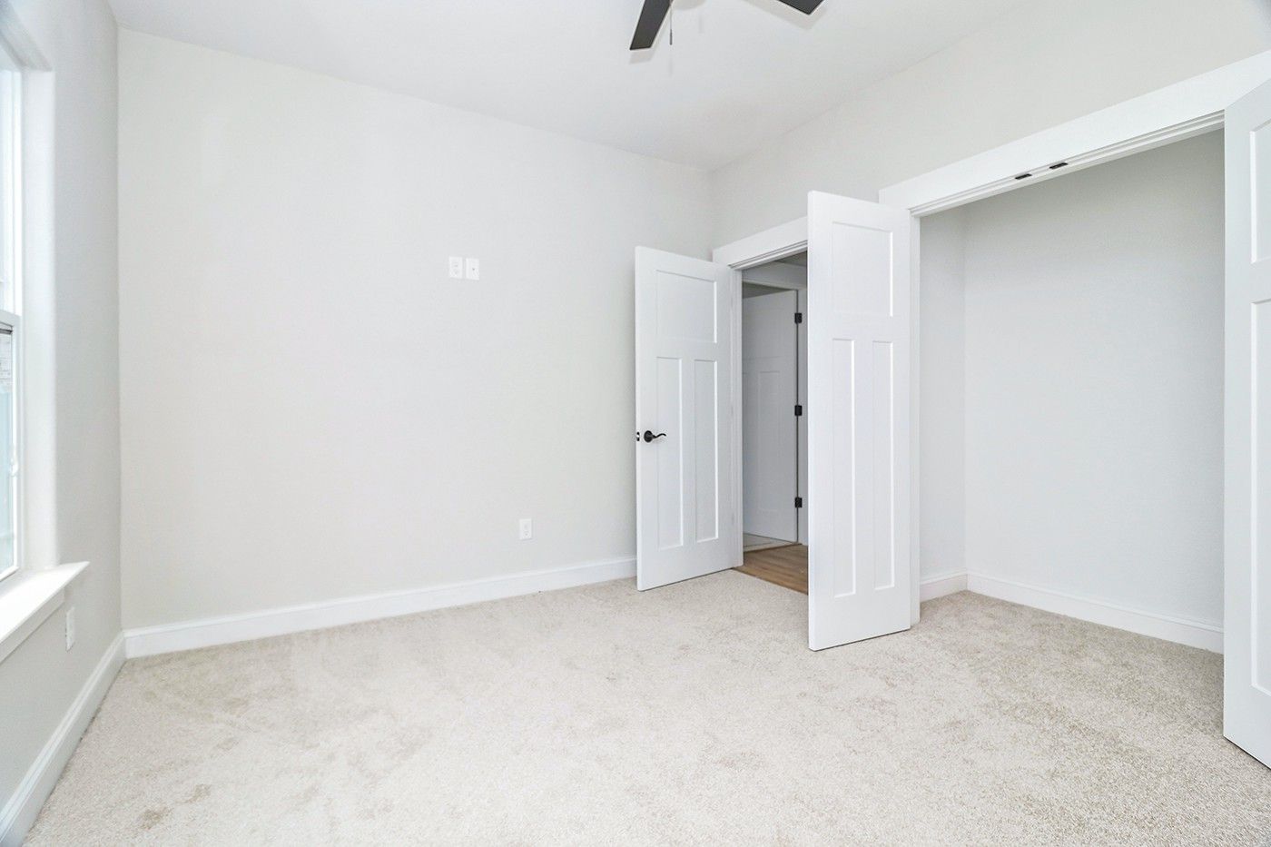 An empty bedroom with a ceiling fan and a closet.