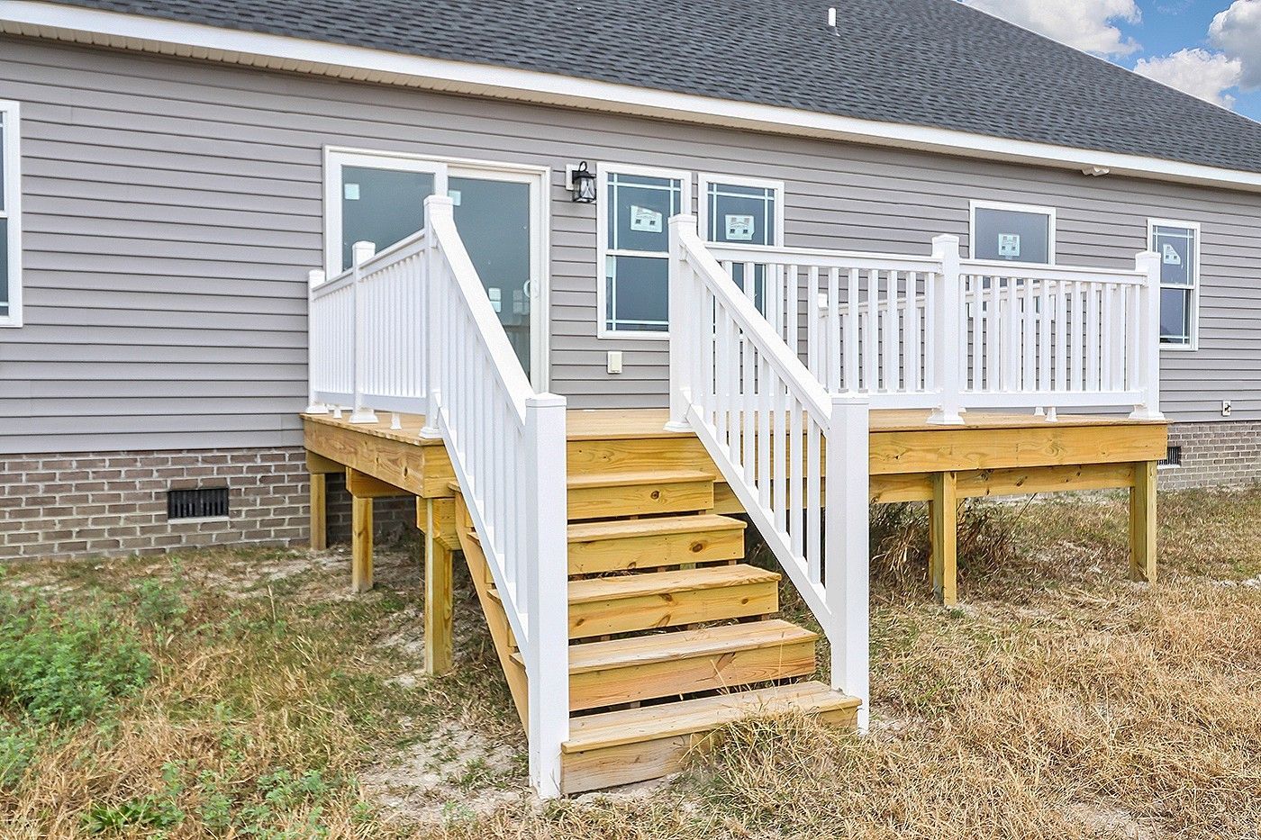 A large deck with stairs leading up to it is in front of a house.