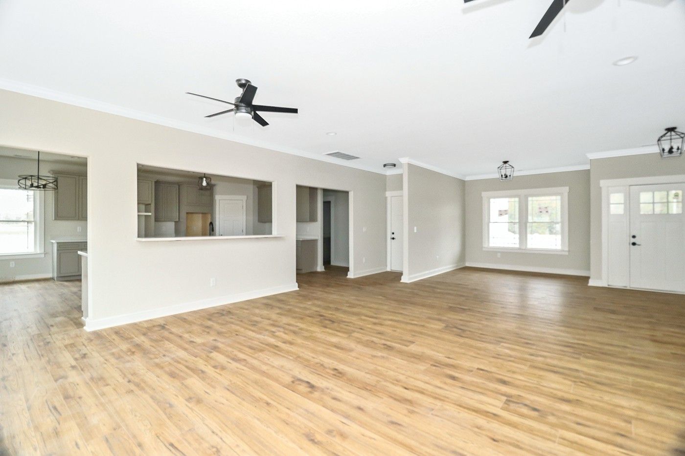 An empty living room with hardwood floors and a ceiling fan.
