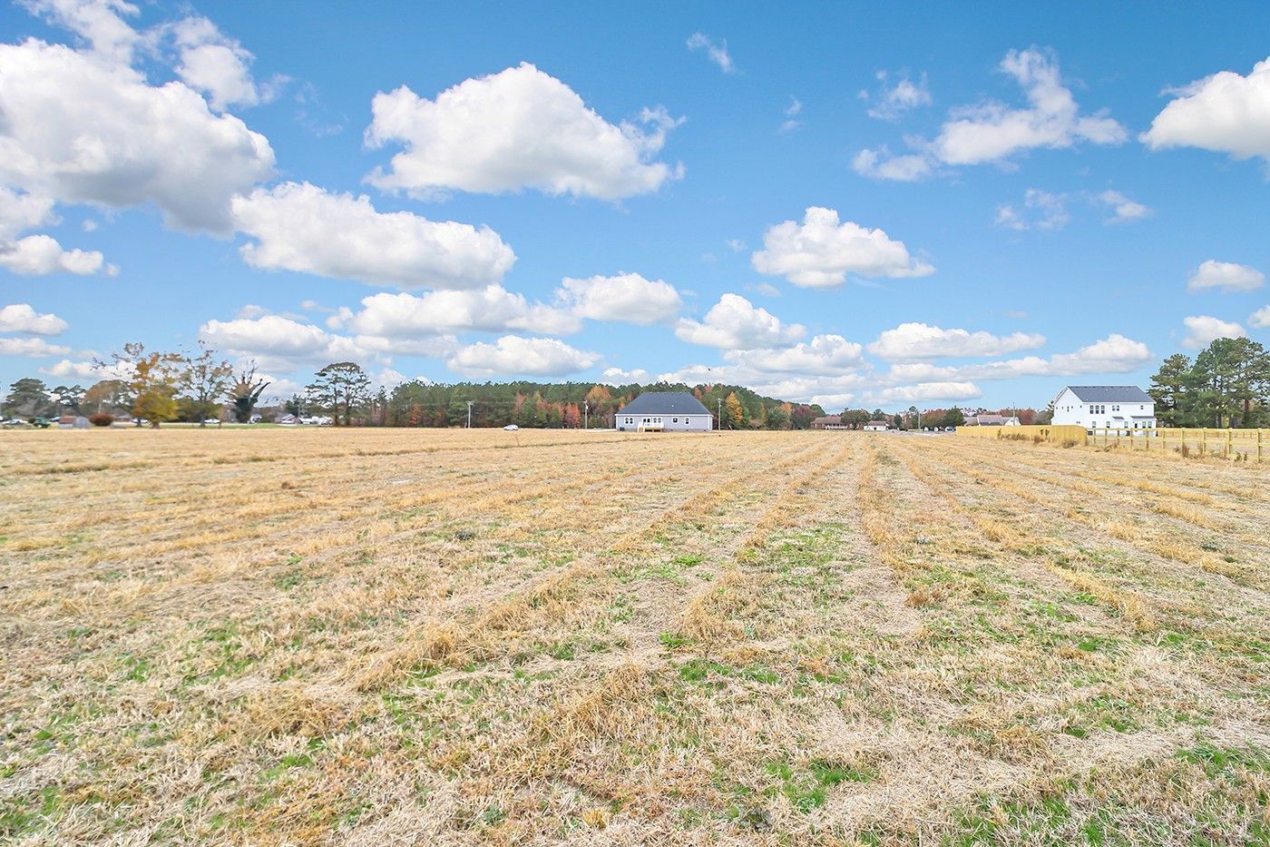 A large empty field with a blue sky and clouds in the background.