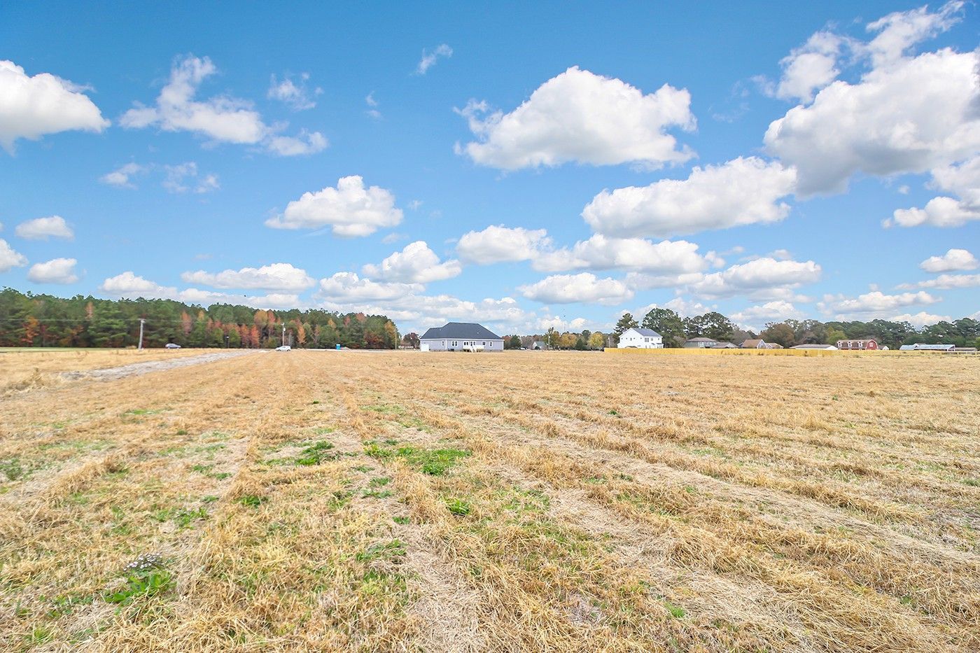 A large empty field with a blue sky and clouds in the background.