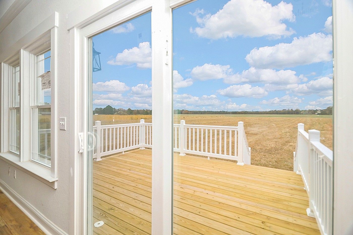 A sliding glass door leading to a wooden deck with a white railing.