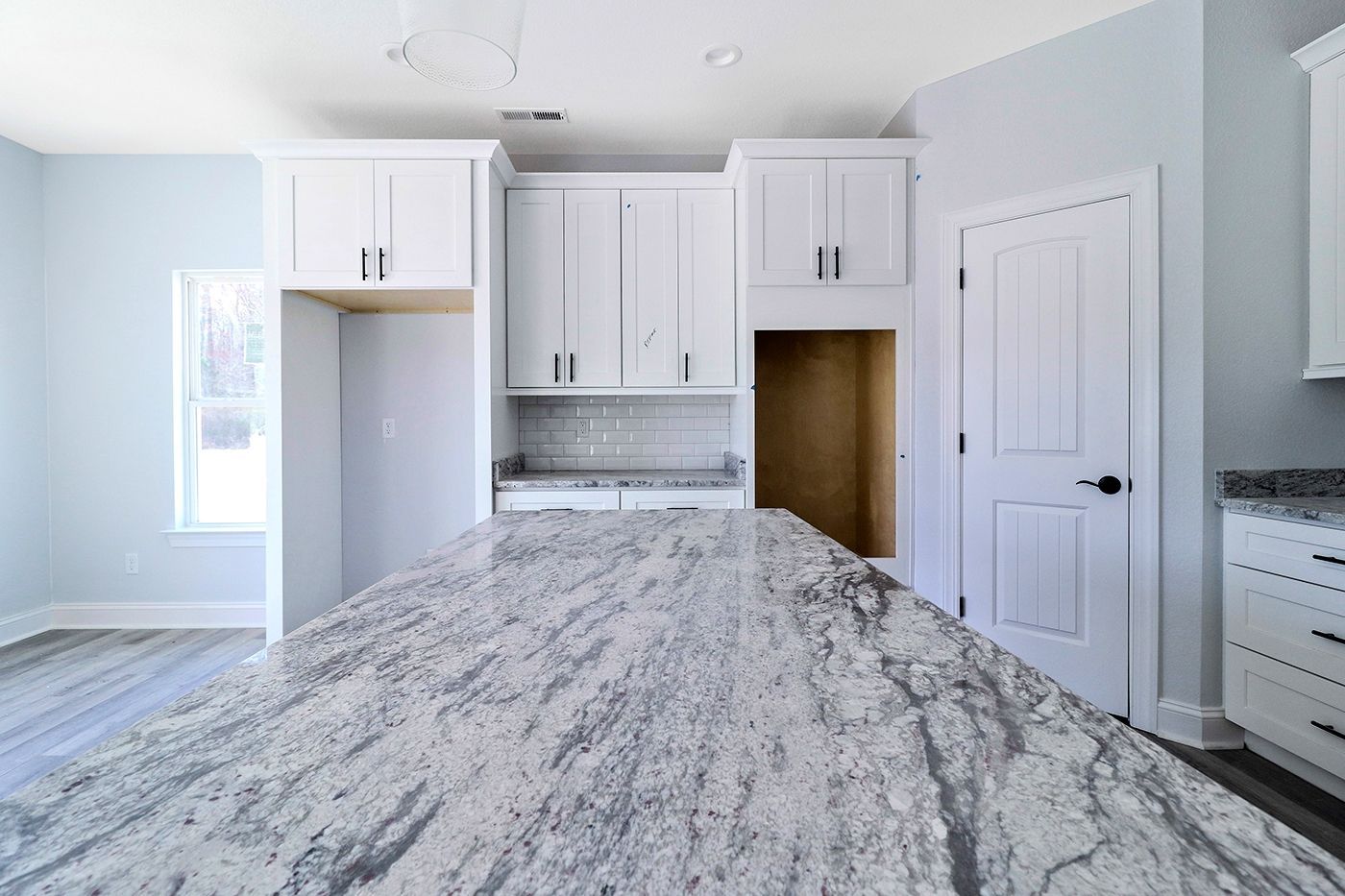 A kitchen with a large granite counter top and white cabinets.