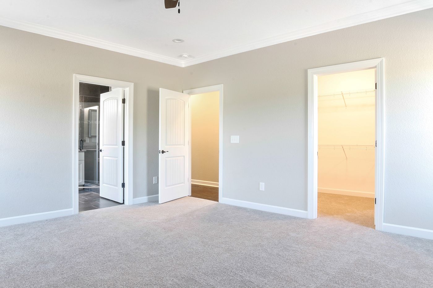 An empty bedroom with a ceiling fan and a walk in closet.