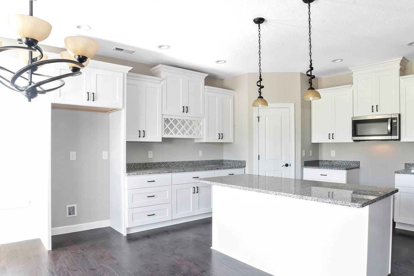 An empty kitchen with white cabinets and granite counter tops