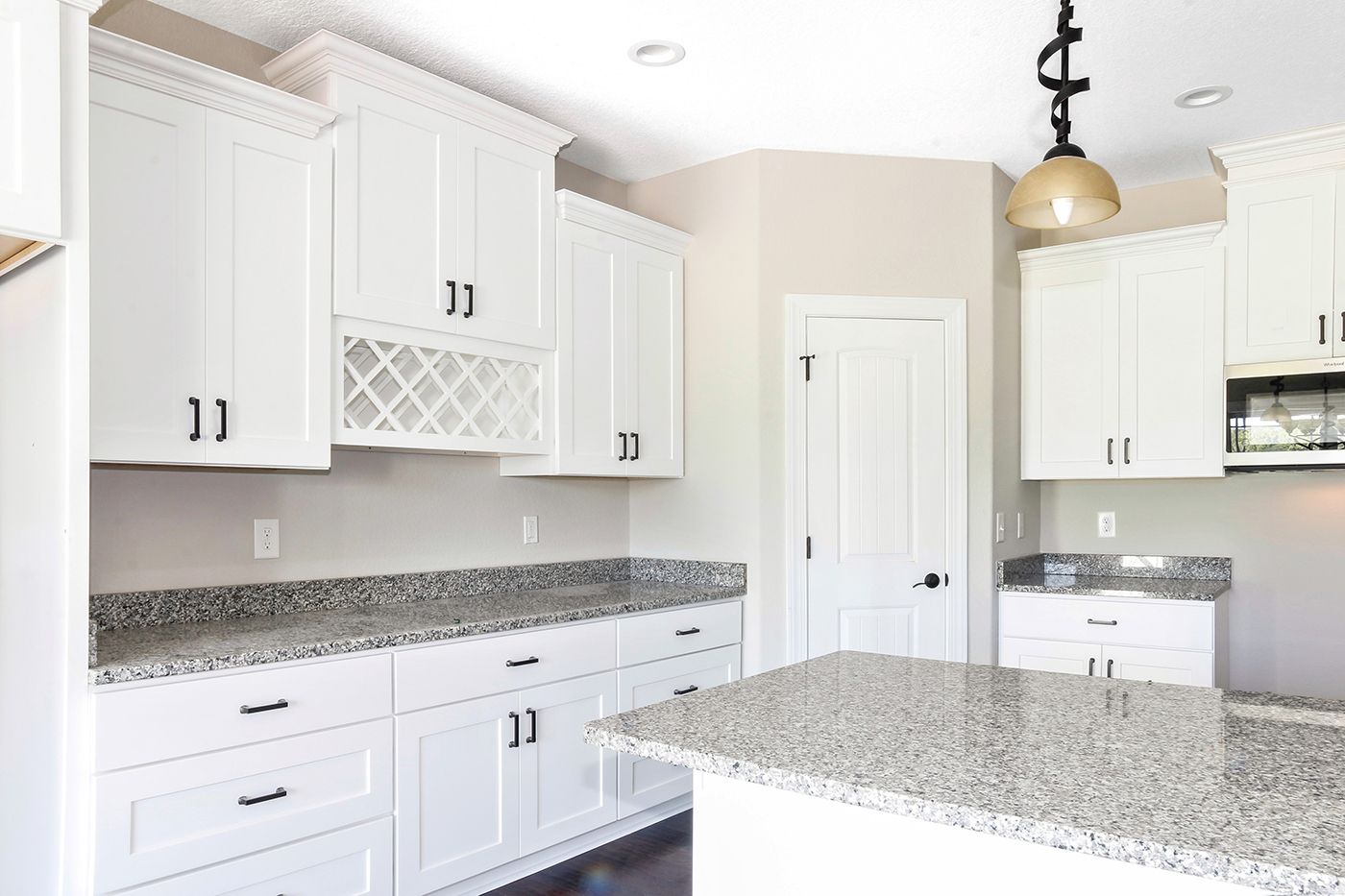 A kitchen with white cabinets and granite counter tops.