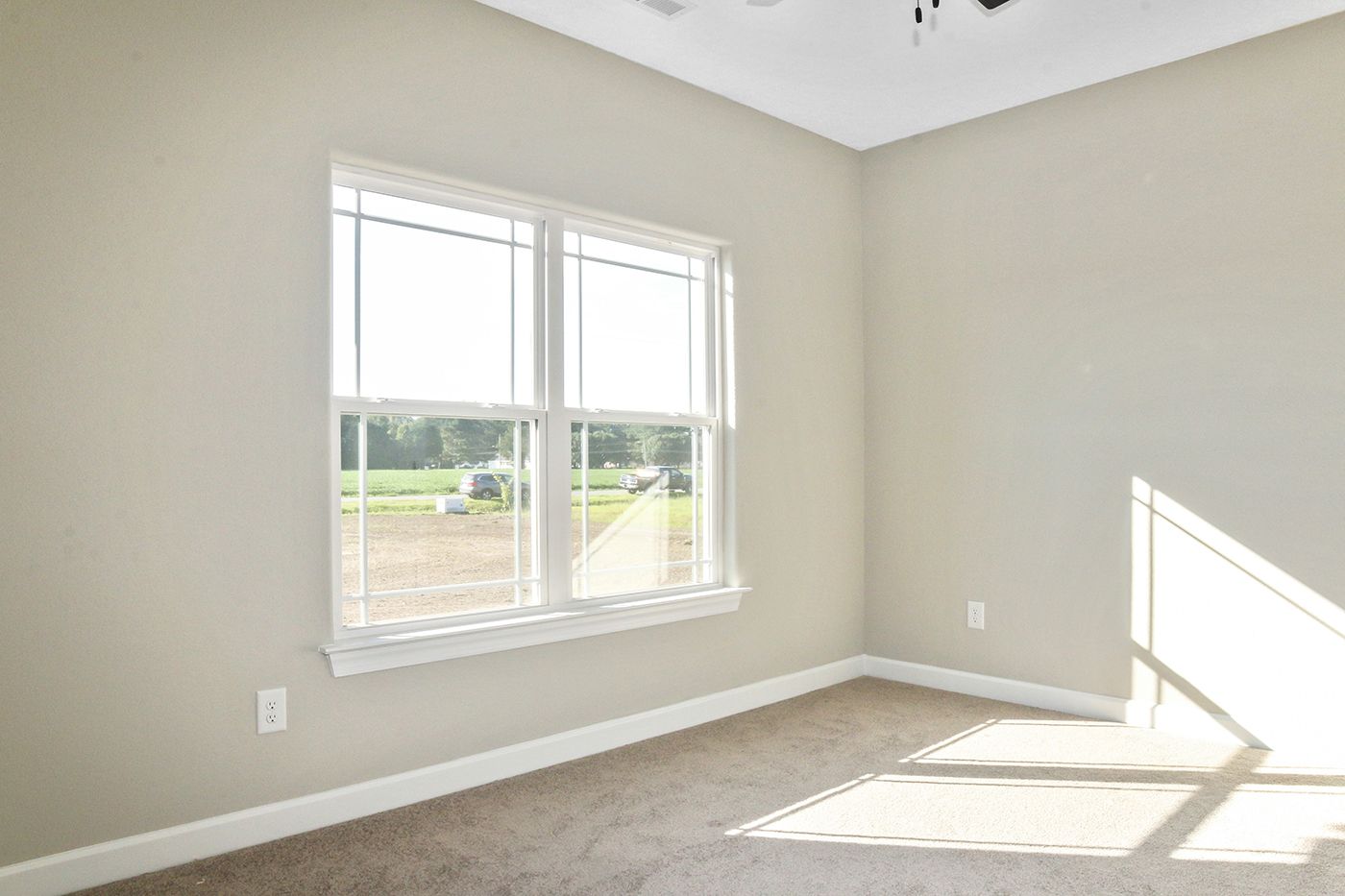 An empty room with two windows and a ceiling fan.