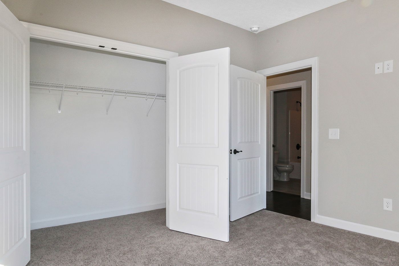 An empty bedroom with a closet and a toilet.