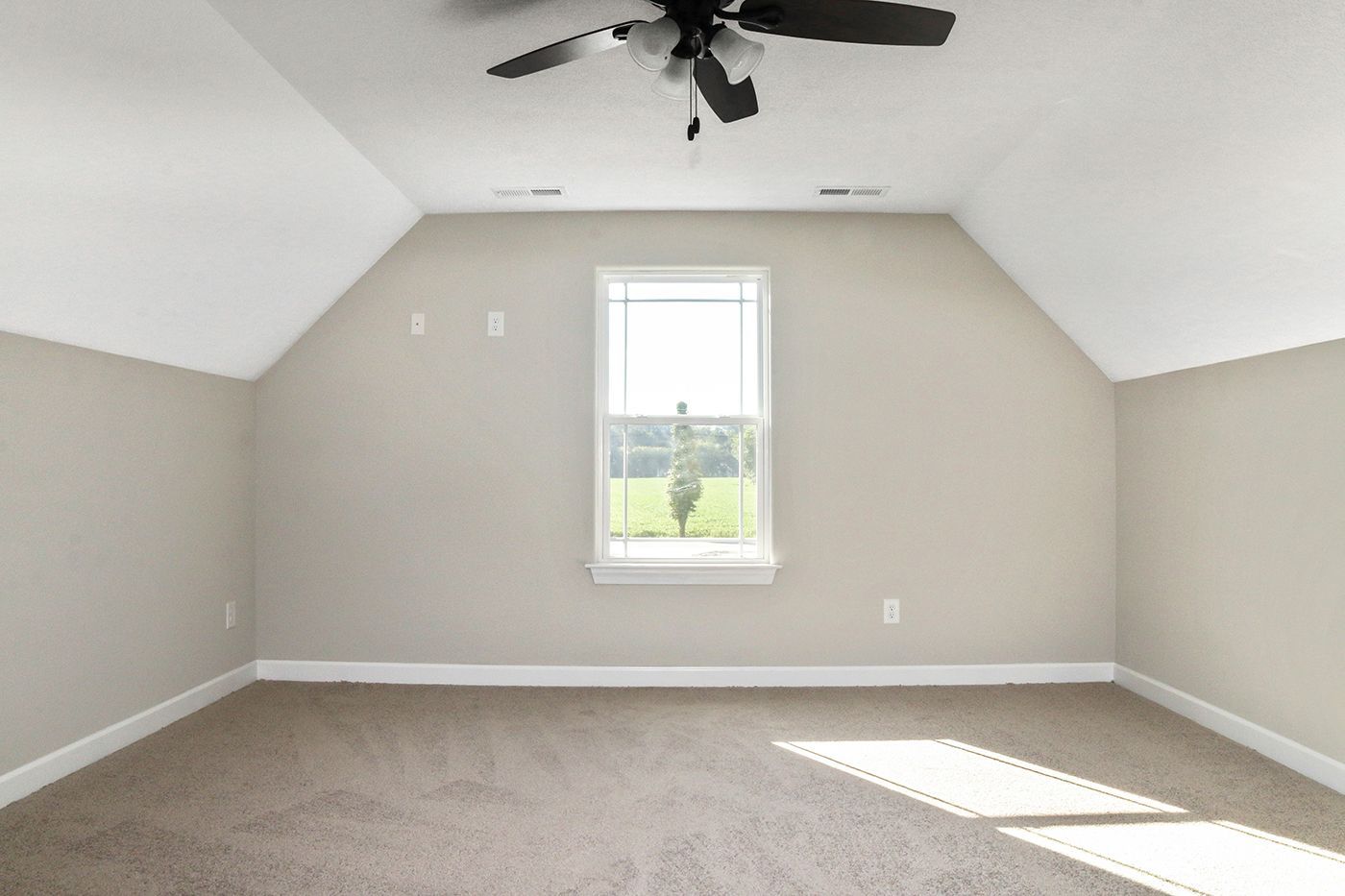 An empty bedroom with a ceiling fan and a window.