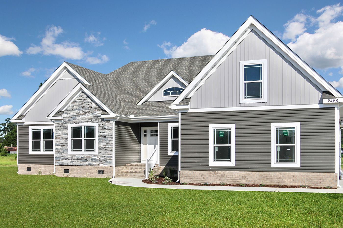 A large house with a lot of windows is sitting on top of a lush green field.