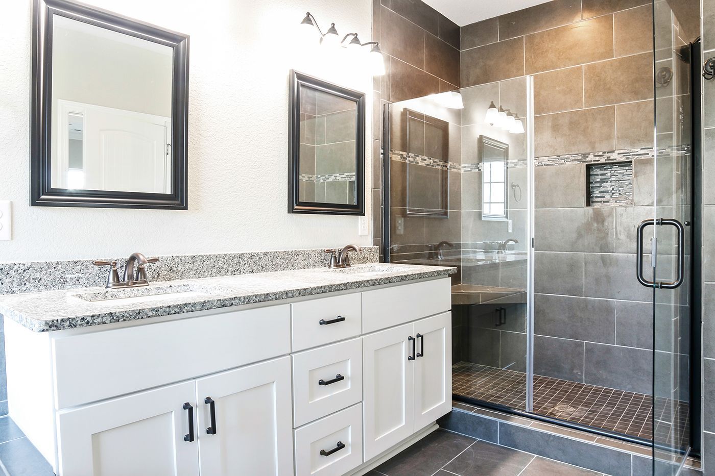 A bathroom with two sinks and a walk in shower.