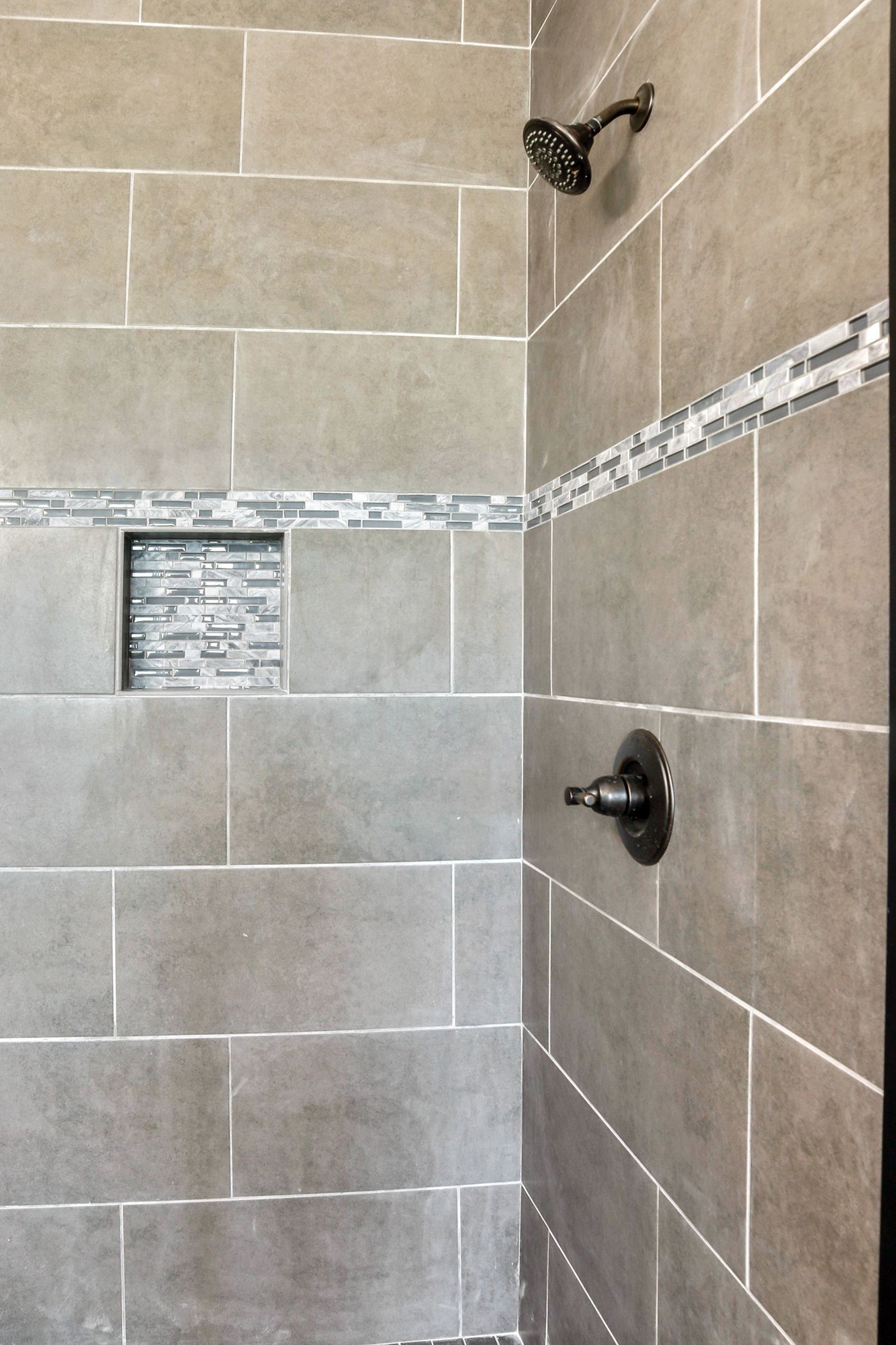A shower with tiled walls and a shower head on the wall.