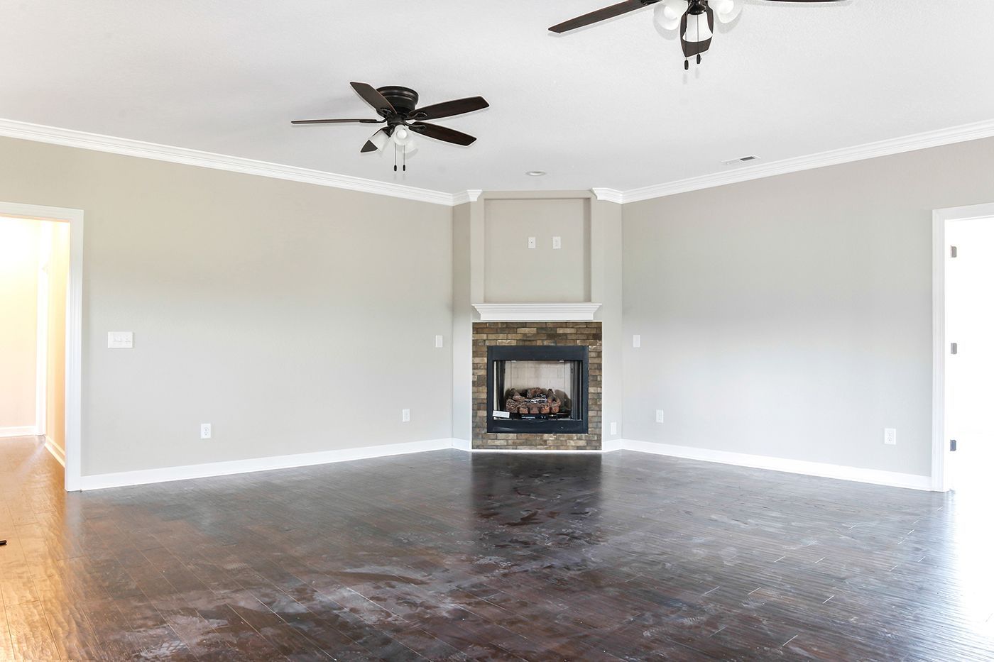 An empty living room with a fireplace and ceiling fan.