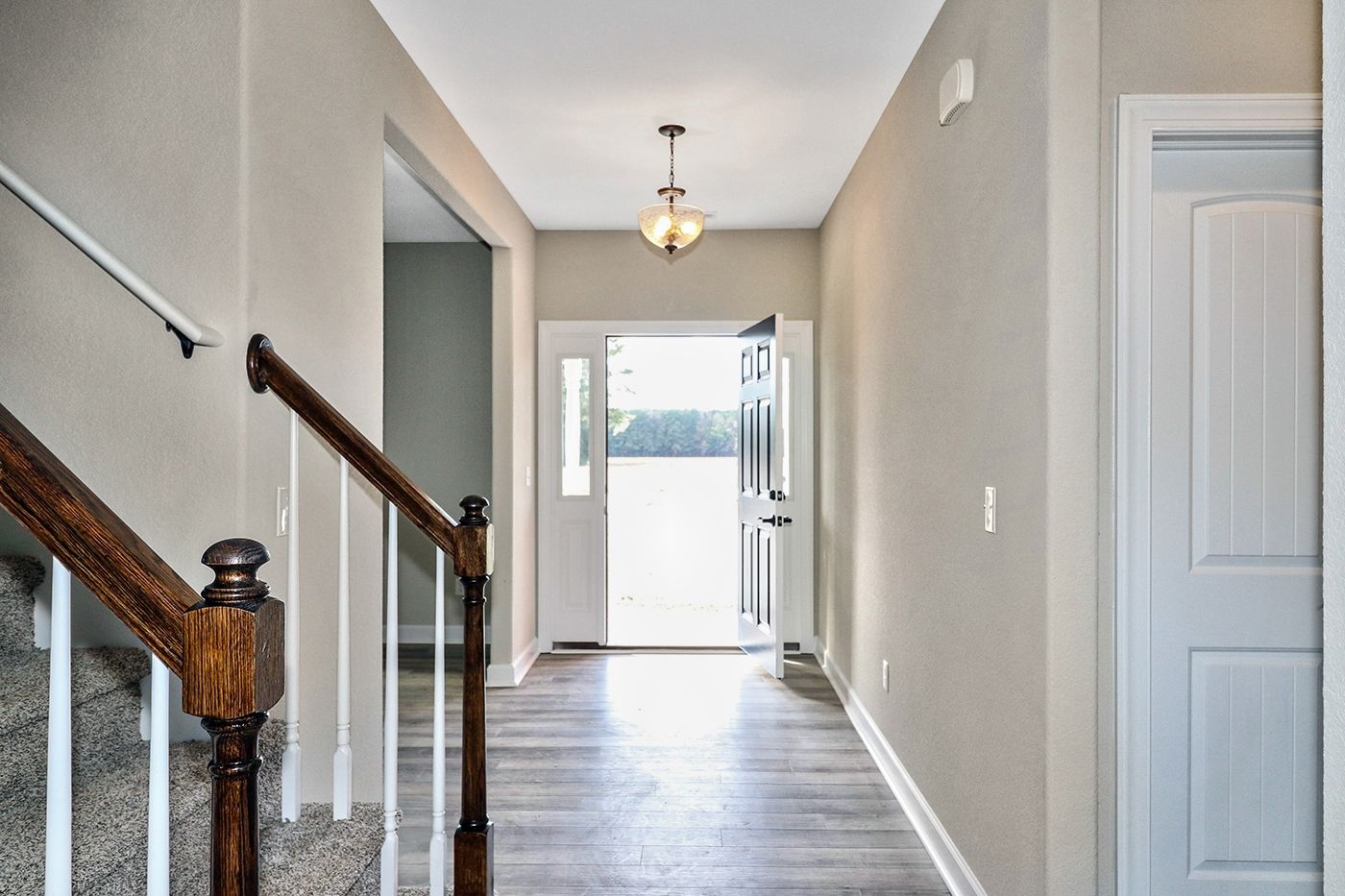 A hallway with stairs leading up to the front door of a house