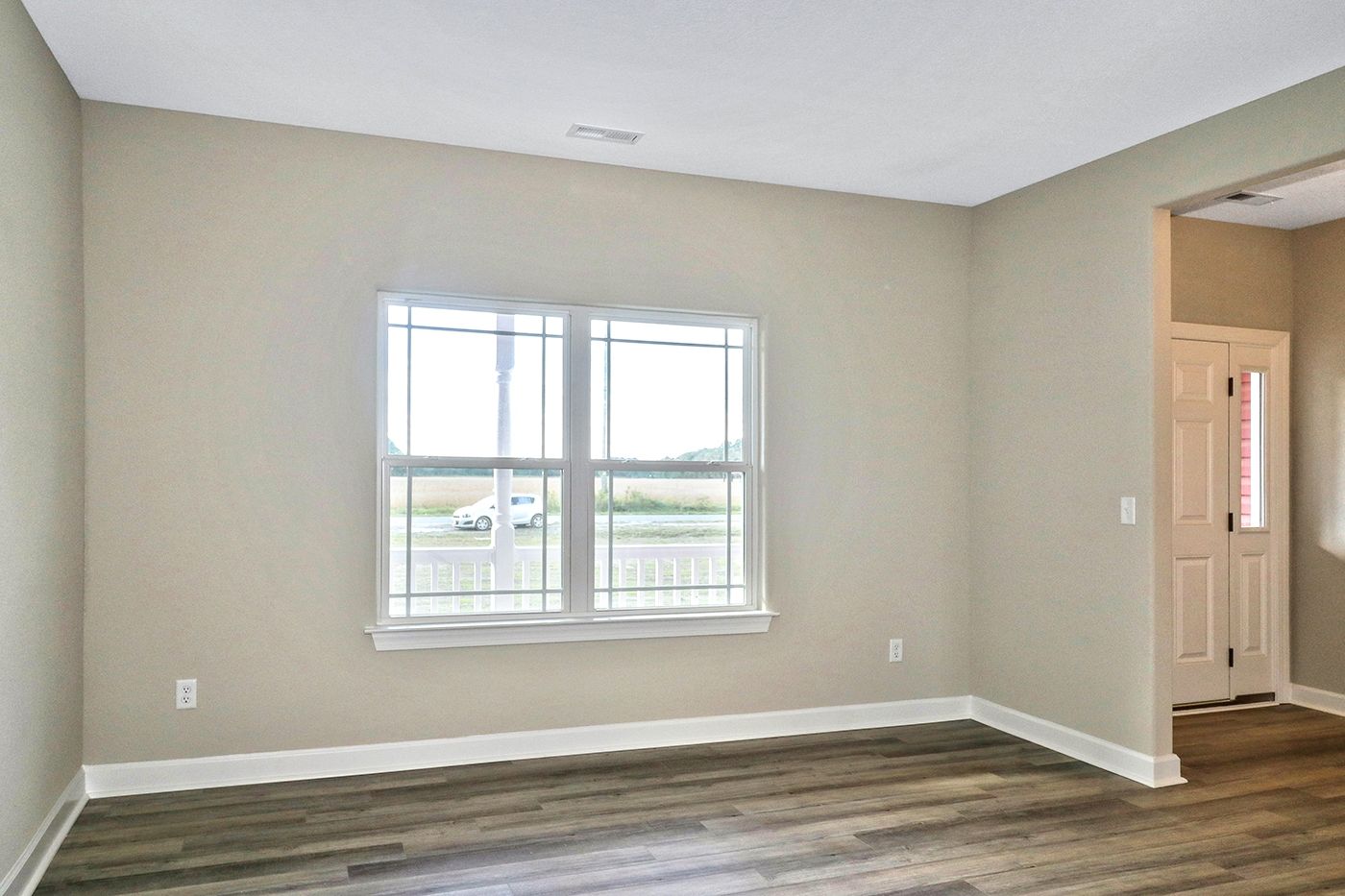 An empty living room with hardwood floors and a window.