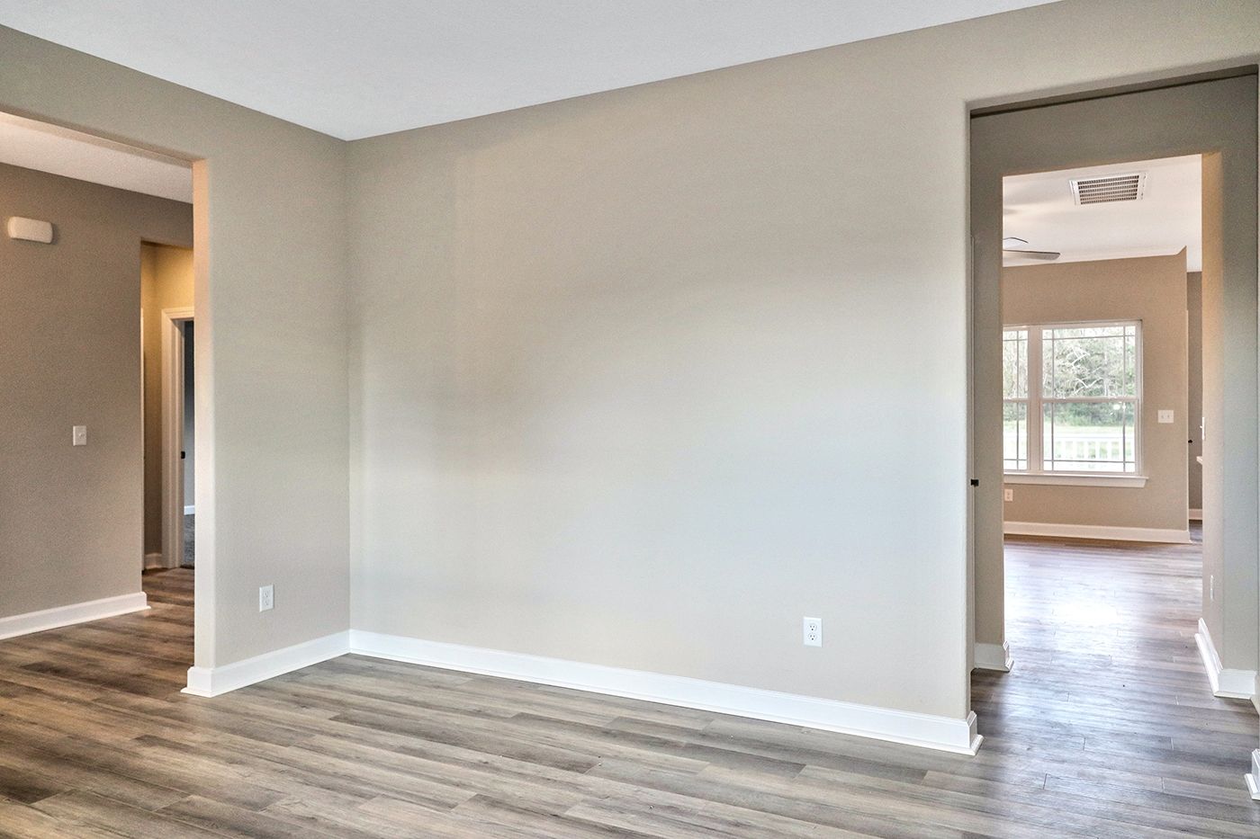 An empty room with hardwood floors and a white wall.