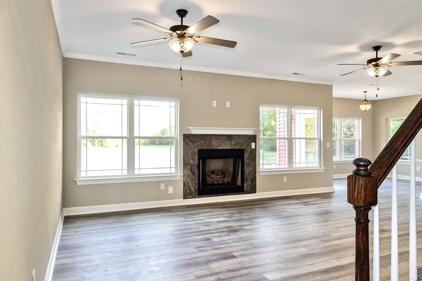 An empty living room with a fireplace and a ceiling fan.