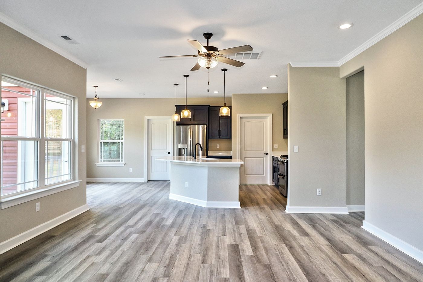 A large empty room with hardwood floors and a ceiling fan.