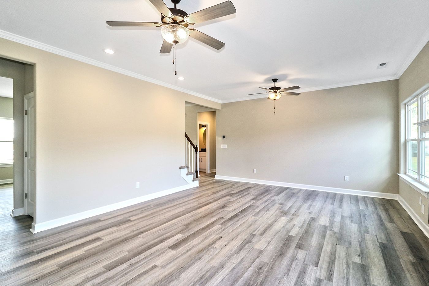 An empty living room with hardwood floors and a ceiling fan.