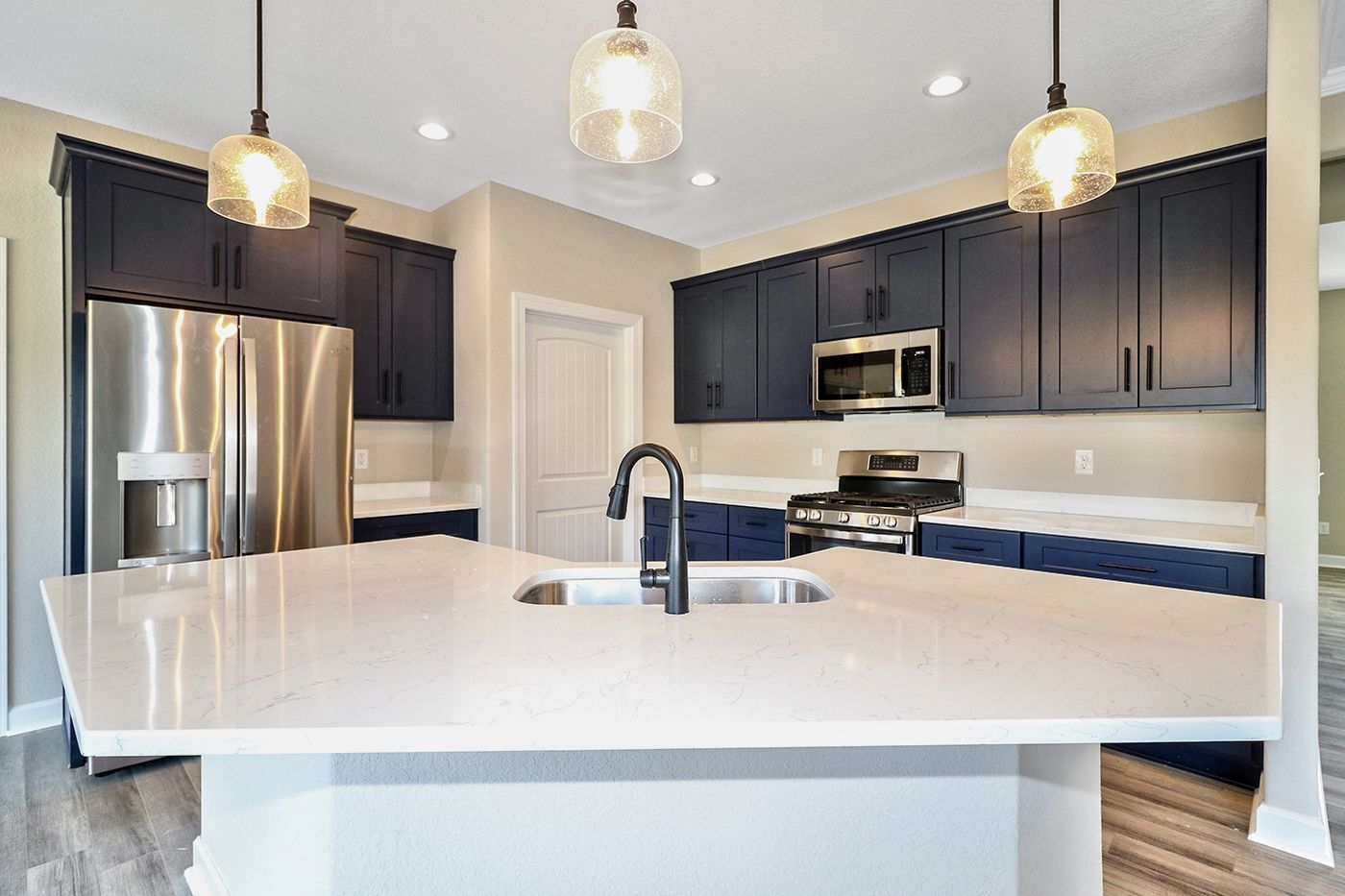 A kitchen with blue cabinets , stainless steel appliances , a sink and a refrigerator.