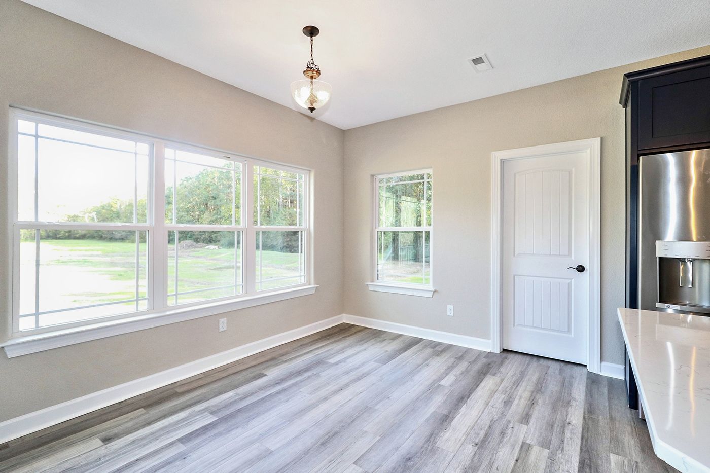 An empty room with hardwood floors and lots of windows.
