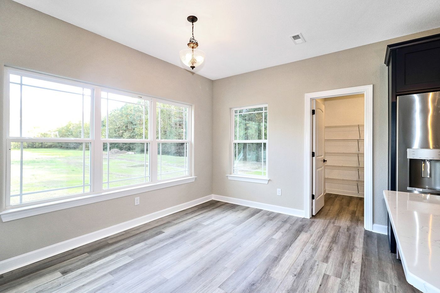 An empty room with hardwood floors and lots of windows.