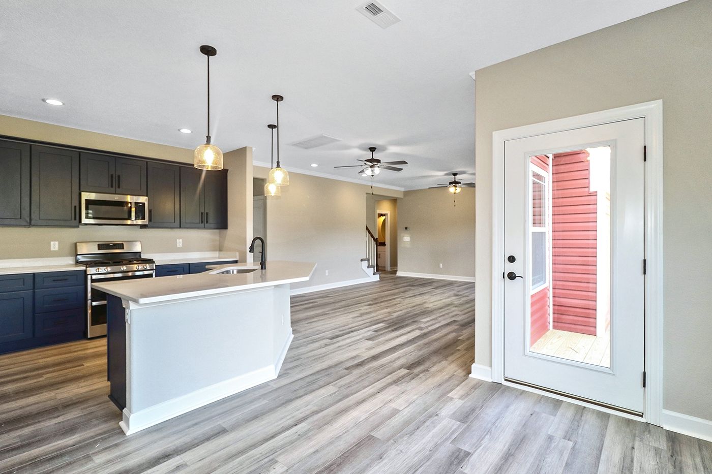 A kitchen and living room in a new home with hardwood floors.