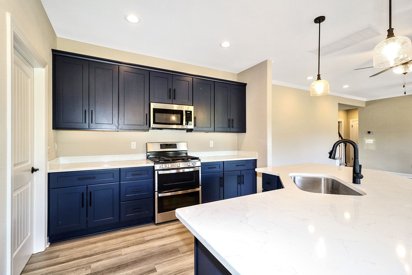 A kitchen with blue cabinets , stainless steel appliances , a sink , and a microwave.