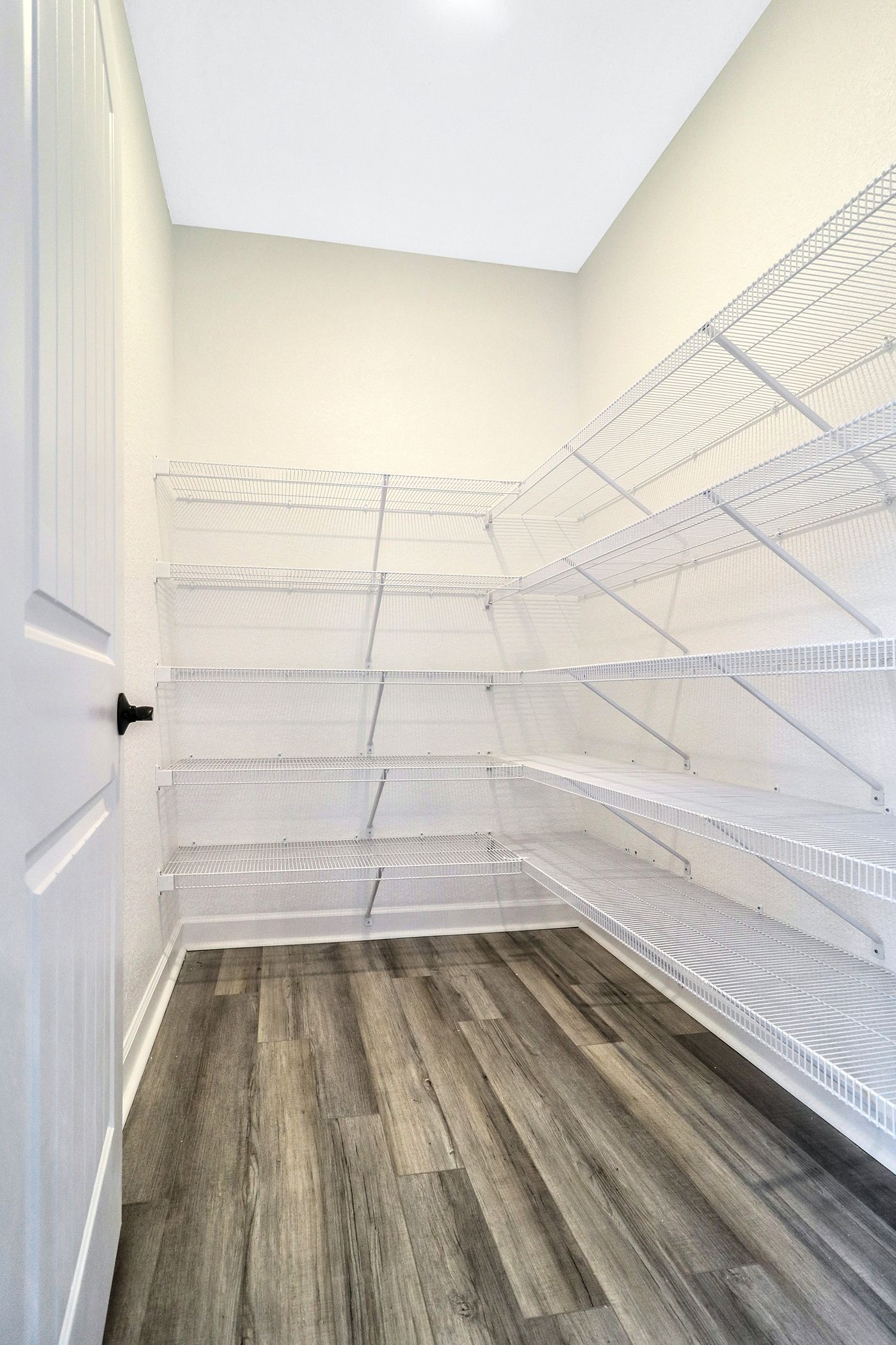A walk in closet with lots of shelves and a wooden floor.