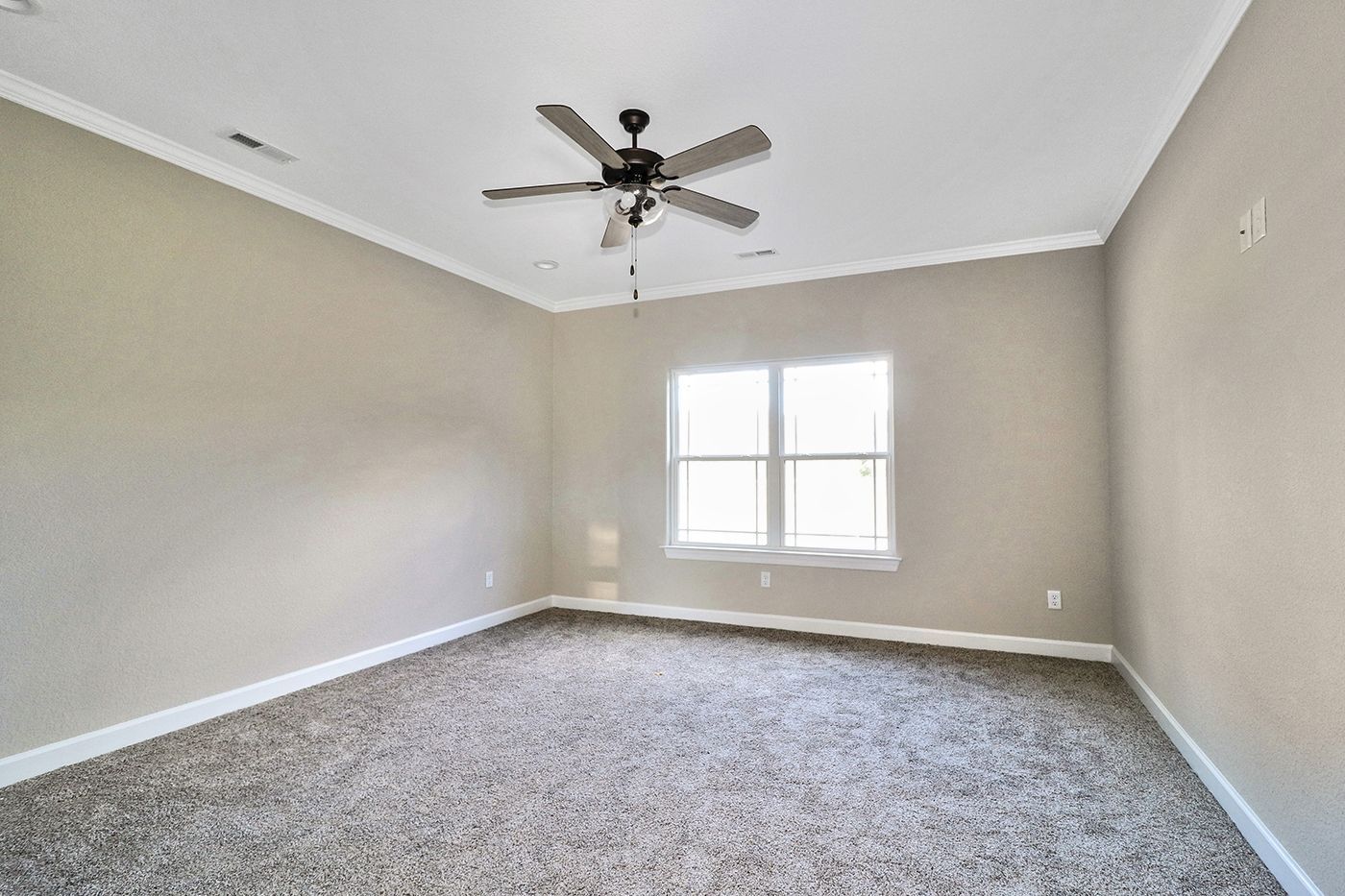 An empty bedroom with a ceiling fan and a window.