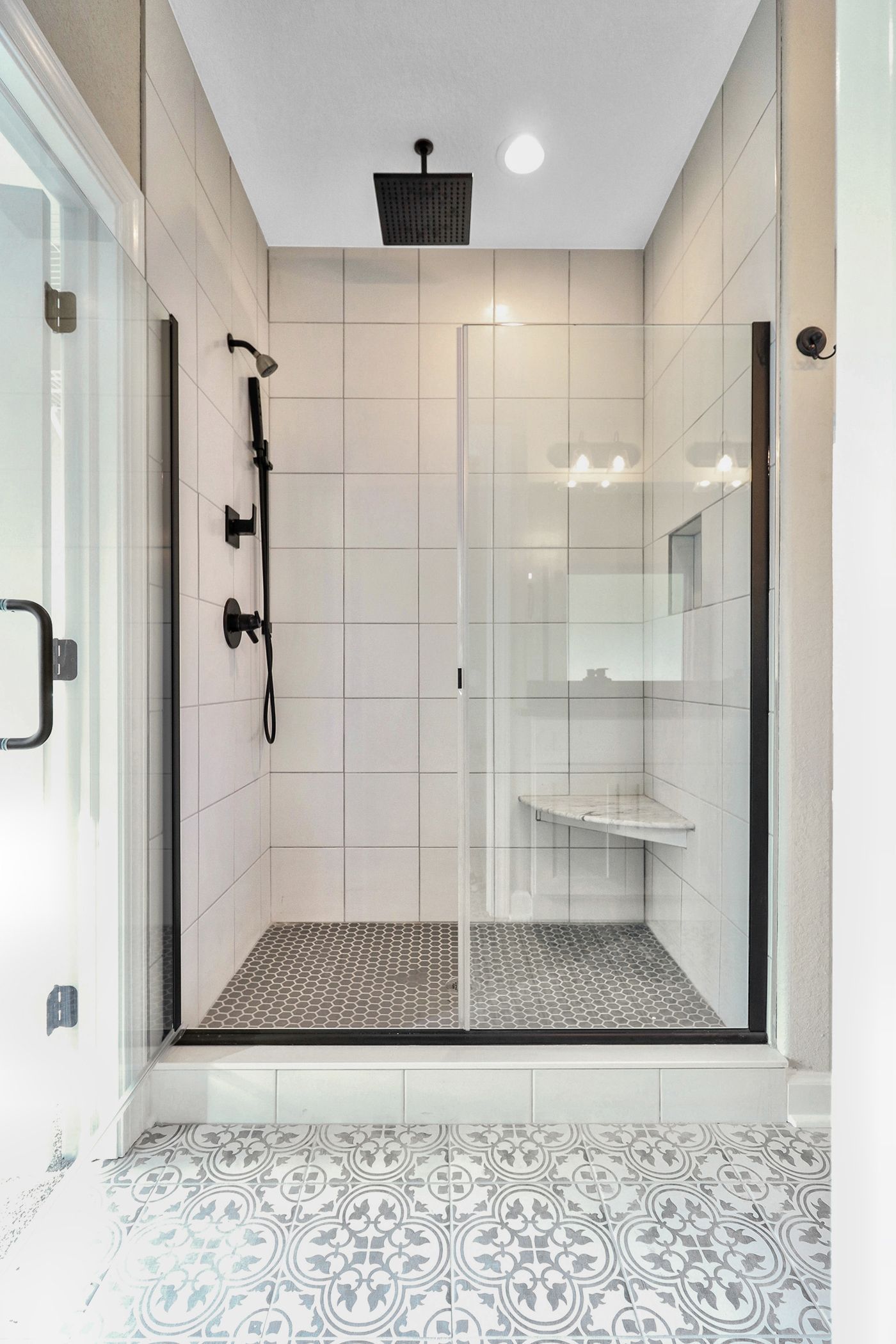A bathroom with a walk in shower with a glass door.