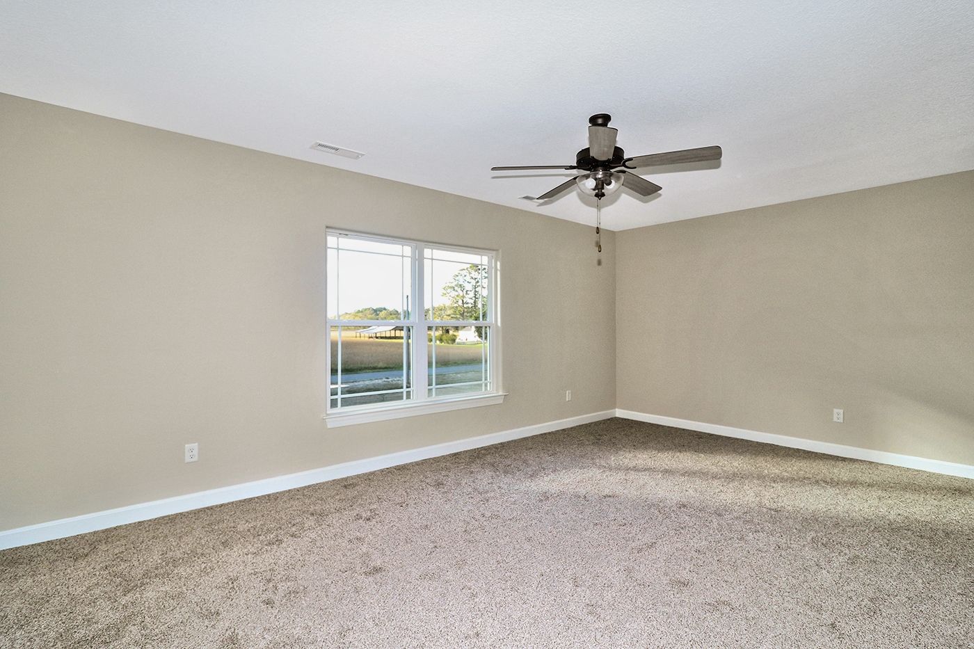 An empty bedroom with a ceiling fan and two windows.