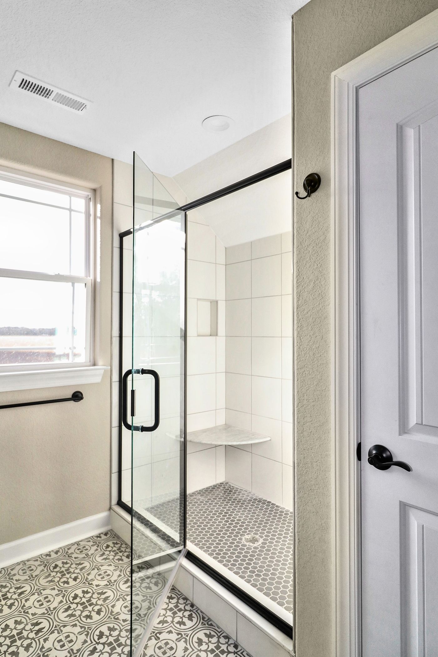 A bathroom with a walk in shower and a window.