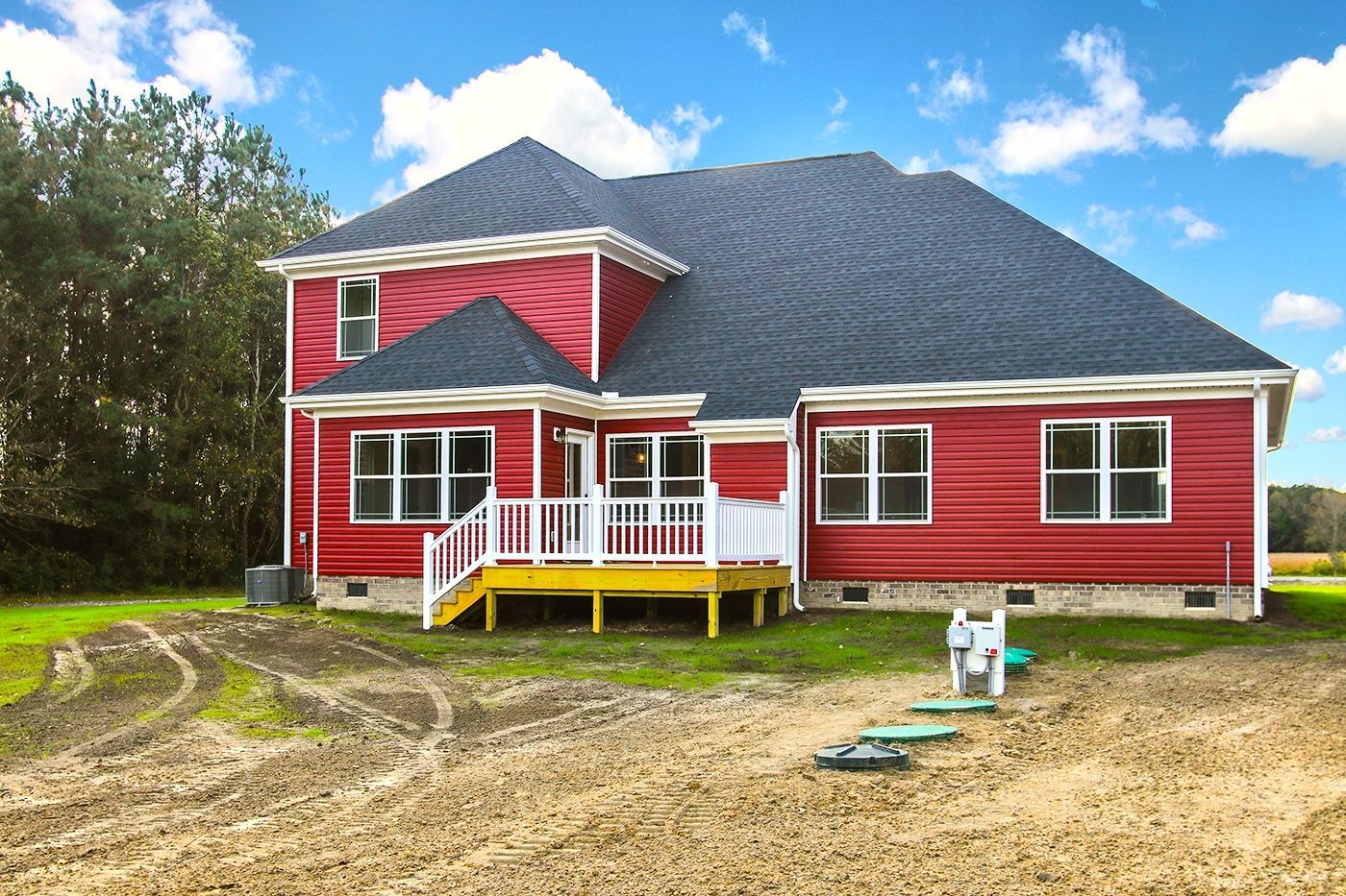 A red house with a black roof and a yellow deck