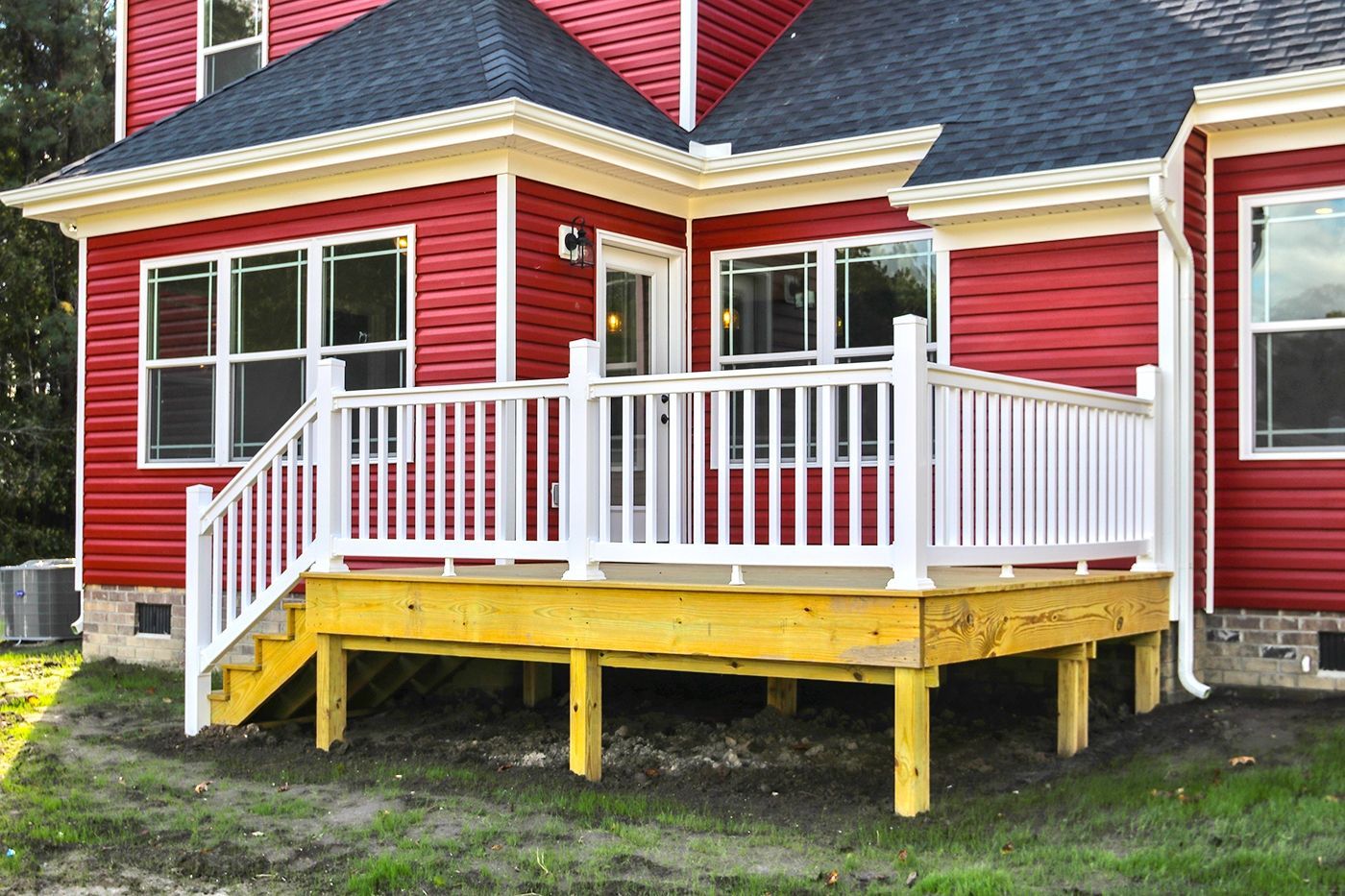 A red house with a white deck in front of it.