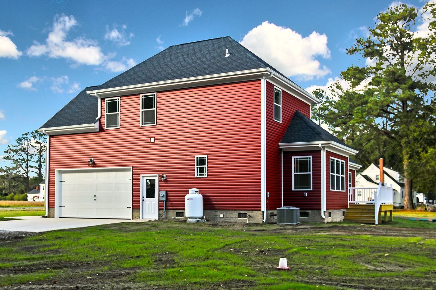 A red house with a black roof and a white garage door