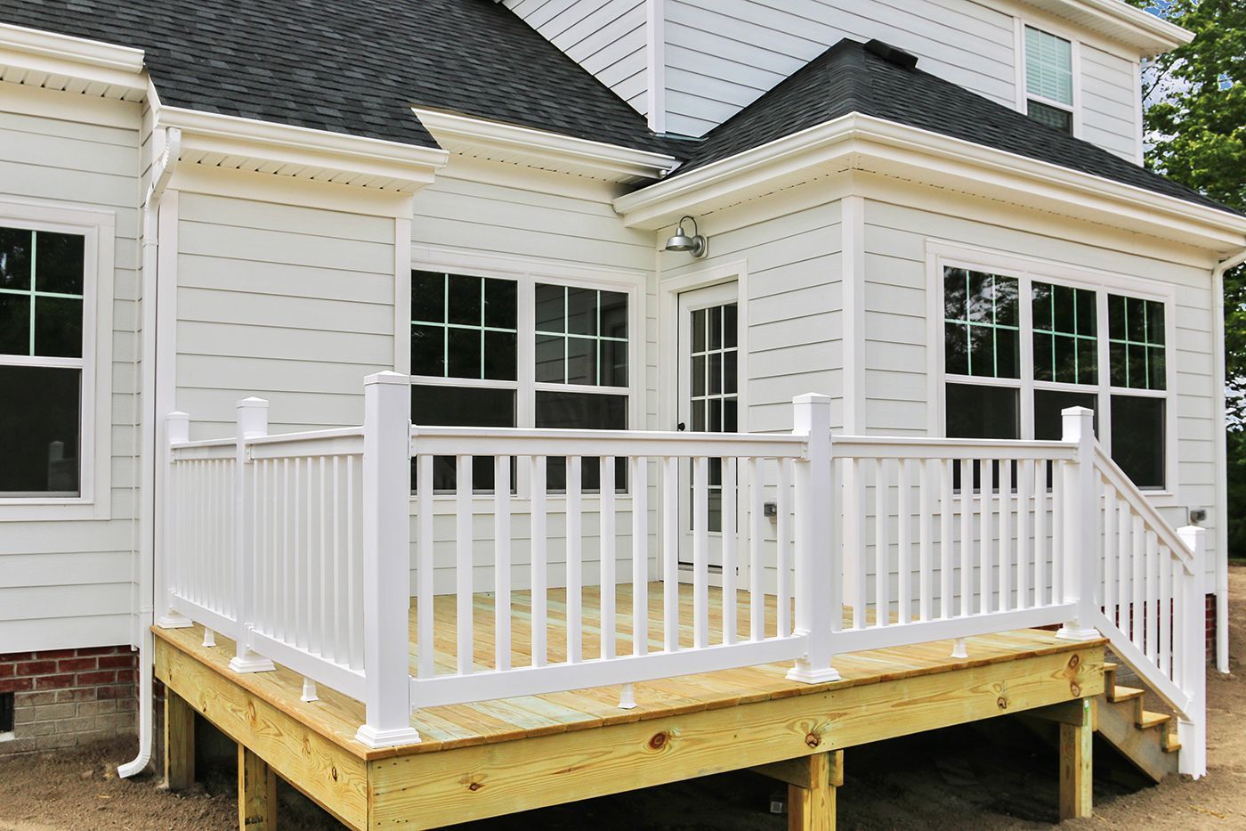 A white house with a wooden deck and white railing.