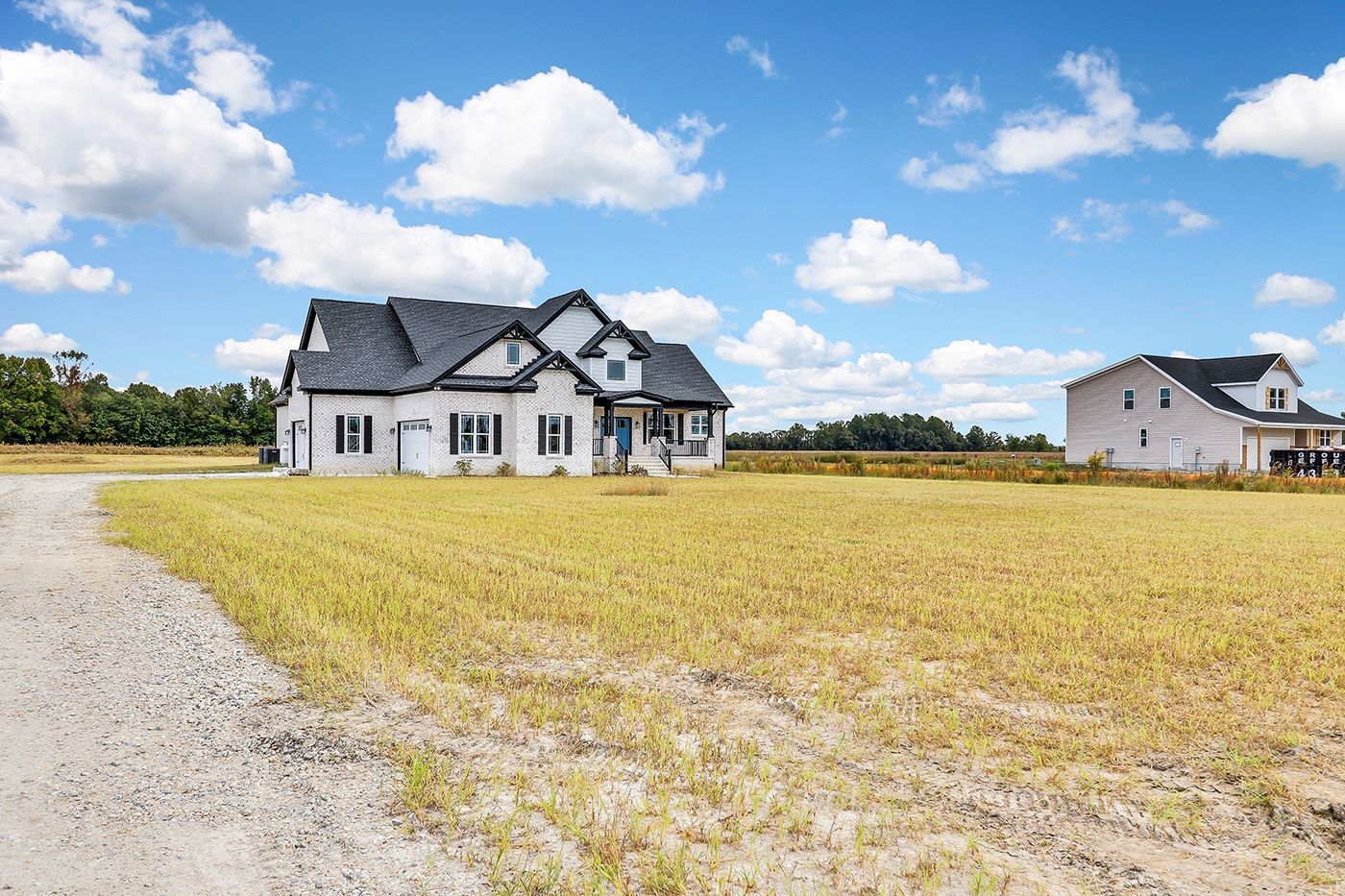 A large white house is sitting on top of a lush green field.