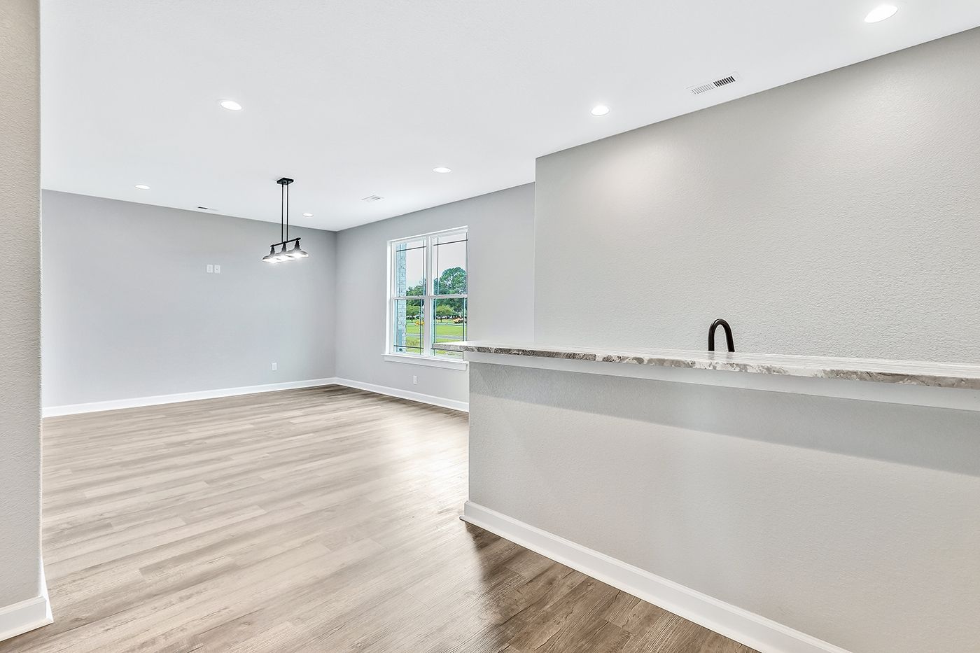 An empty living room with hardwood floors and a marble counter top.
