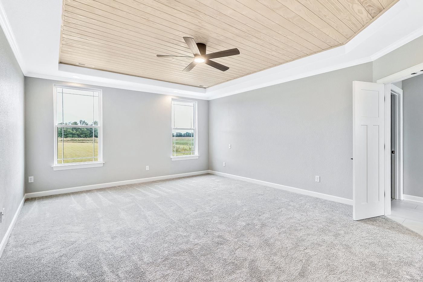 An empty bedroom with a ceiling fan and gray carpet.