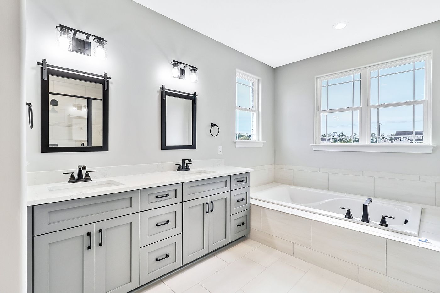 A bathroom with two sinks , two mirrors and a tub.