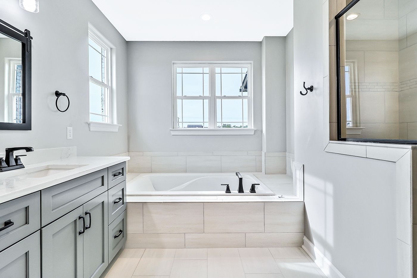 A bathroom with a tub , sink , mirror and window.