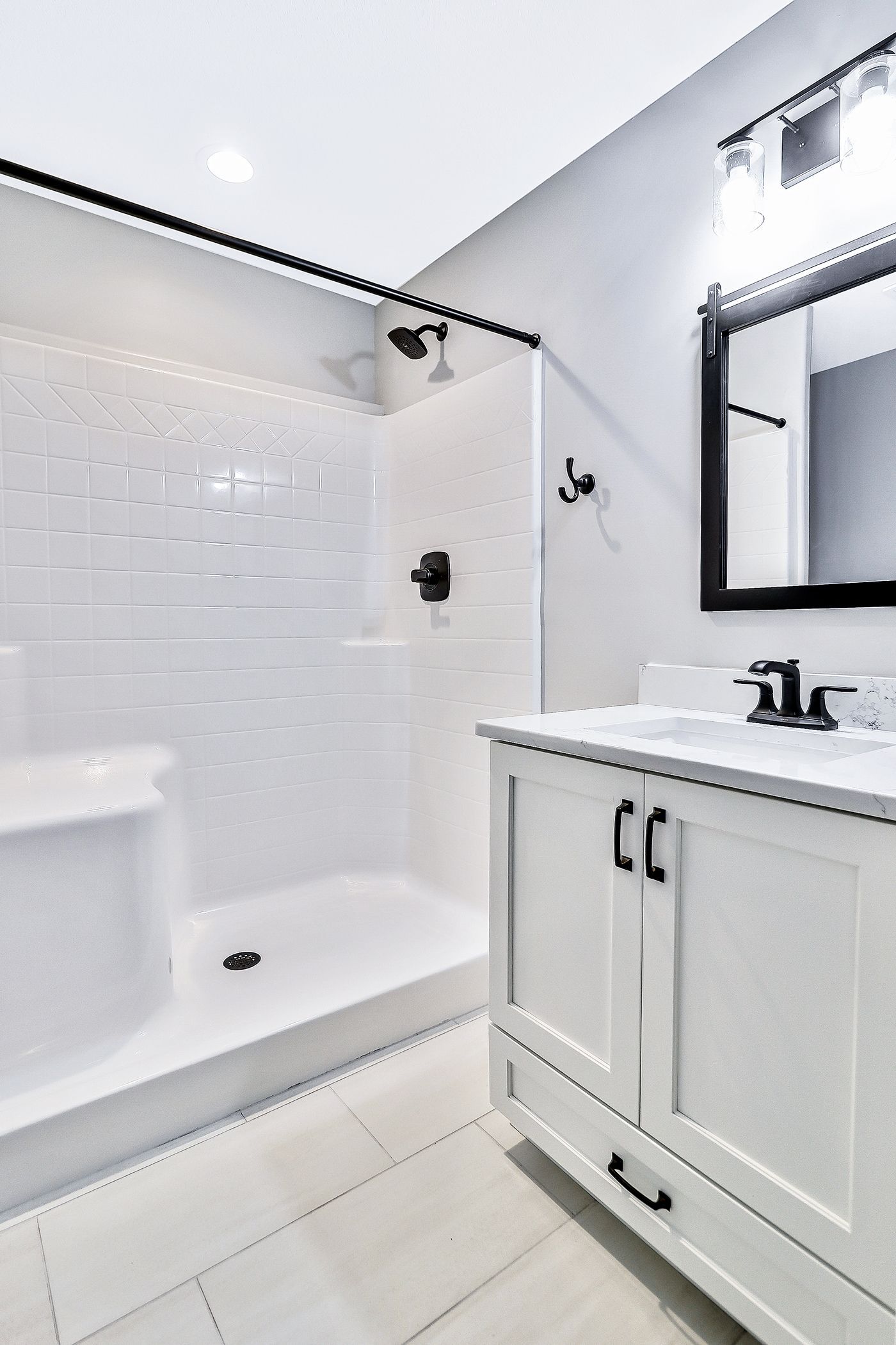 A bathroom with a sink , mirror and shower.