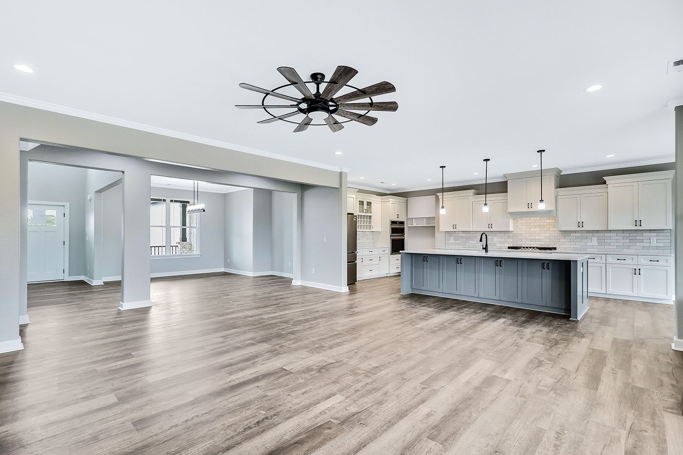 A large empty kitchen with a ceiling fan and hardwood floors.