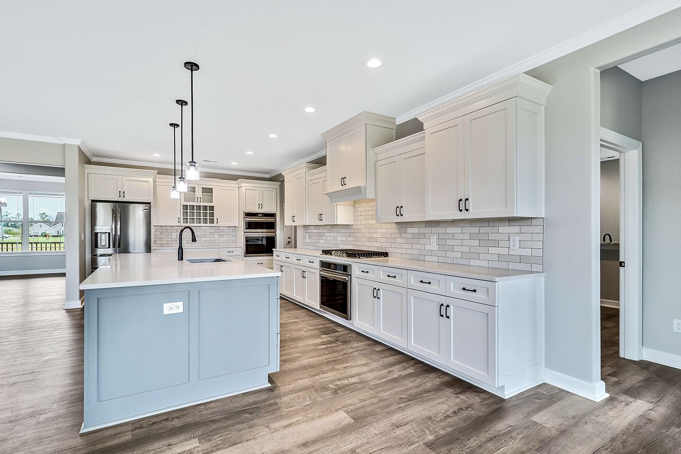 A kitchen in a new home with white cabinets and a large island.